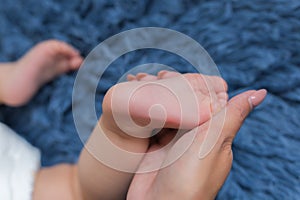 Baby feet in mother hands. Tiny Newborn Baby`s feet on female Shaped hands closeup. Mom and her Child. Happy Family