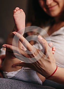 Baby feet in mother hands. Tiny Newborn Baby`s feet on female Shaped hands closeup. Mom and her Child. Happy Family