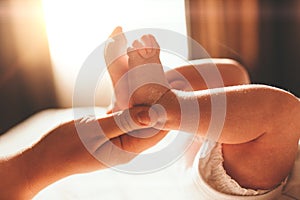 Baby feet in mother hands. Tiny Newborn Baby`s feet on female Shaped hands closeup. Mom and her Child. Happy Family