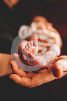 Baby feet in mother hands. Tiny Newborn Baby`s feet on female Shaped hands closeup. Mom and her Child. Happy Family