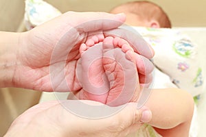 Baby feet in mother hands. Tiny Newborn Baby`s feet on female Shaped hands closeup. Mom and her Child. Happy Family concept.