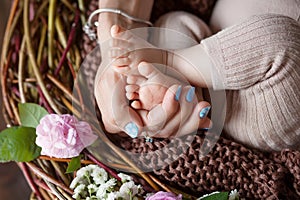 Baby feet in mother hands. Tiny Newborn Baby`s feet on female Shaped hands closeup. Mom and her Child. Happy Family concept.