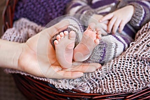 Baby feet in mother hands. Tiny Newborn Baby`s feet on female Shaped hands closeup. Mom and her Child. Happy Family concept.