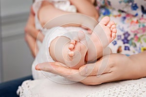 Baby feet in mother hands. Tiny Newborn Baby`s feet on female Shaped hands closeup. Mom and her Child. Happy Family concept.