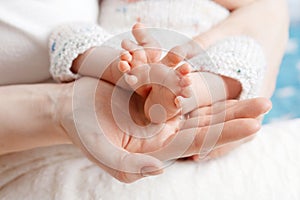 Baby feet in mother hands. Tiny Newborn Baby`s feet on female Shaped hands closeup. Mom and her Child. Happy Family concept.