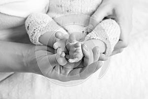 Baby feet in mother hands. Tiny Newborn Baby`s feet on female Shaped hands closeup. Mom and her Child. Happy Family concept.