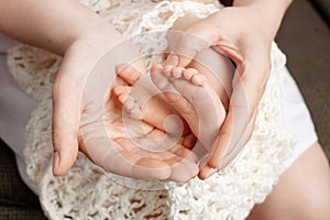 Baby feet in mother hands. Tiny Newborn Baby`s feet on female Shaped hands closeup. Mom and her Child. Happy Family concept.