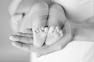 Baby feet in mother hands. Tiny Newborn Baby`s feet on female Shaped hands closeup. Mom and her Child. Happy Family concept.