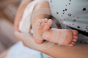 Baby feet in mother hands. Tiny Newborn Baby`s feet on female Shaped hands closeup. Mom and her Child. Happy Family concept.