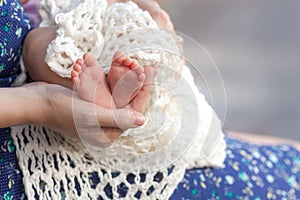 Baby feet in mother hands. Tiny Newborn Baby`s feet on female Shaped hands closeup. Mom and her Child. Happy Family concept.