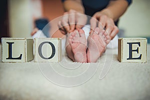 Baby feet in mother hands. Tiny Newborn `s on female Heart Shaped closeup.