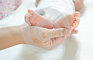 Baby feet are near the mother`s hand. Mother`s love