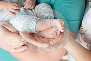 Baby feet in parents hands. Tiny Newborn Baby`s feet on parents shaped hands closeup. Parents and they Child. Happy Family concep