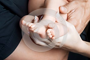 Baby feet in parents hands. Tiny Newborn Baby`s feet on parents shaped hands closeup. Parents and they Child. Happy Family concep