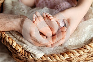 Baby feet in parents hands. Tiny Newborn Baby`s feet on ffamily hands closeup. Mom, dad and they child. Happy Family concept.