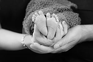 Baby feet in parents hands. Tiny Newborn Baby`s feet on parents shaped hands closeup. Parents and they Child. Happy Family concep