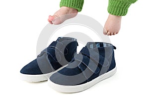 Baby feet with too big blue child shoes isolated on white