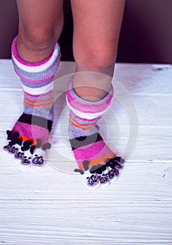 Baby feet in warm, long multicolored socks with toes