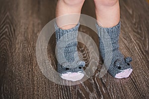 Baby feet in winter mouse socks on the wooden floor