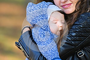 The baby fell asleep in the arms of his mother. the warm embrace of the mother calmed the baby. warm weather for sleeping. safety