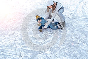 The baby fell on the ice. A young mother skates in the park in winter, with her son a young child 3-5 years old. Weekend
