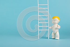 A baby figurine and a ladder on a light blue background. The concept of development and growth