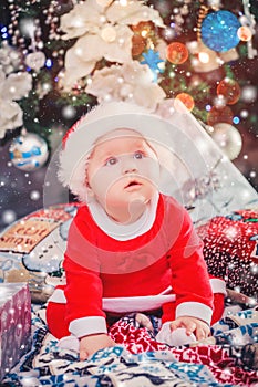 Baby first Christmas. New Year holidays. Baby with santa hat with gift.