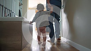 baby first steps with dad. happy family a kid dream concept. dad and baby daughter walk along the corridor of the house