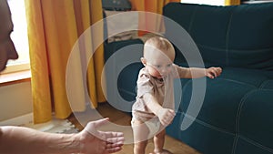 Baby first steps. Dad helps a baby toddler take first steps at home. Happy family kid dream concept. Baby boy learning