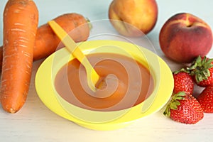 Baby food in bowl and fresh ingredients on wooden table