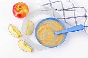 Baby food. Fresh homemade applesauce. Blue bowl with fruit puree on fabric and cut apples on table. The concept of proper