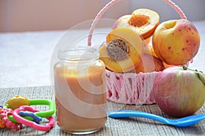 Baby food, baby fruit mashed in a glass jar, peach, beautiful peaches in a basket, children`s toy. apple