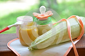 Baby food in jars puree mashed food on a background of foliage, With Zucchini a pacifier and spoon