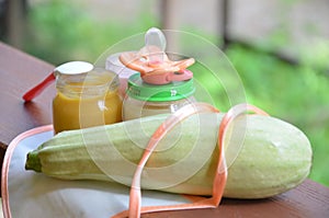 Baby food in jars puree mashed food on a background of foliage, With Zucchini a pacifier and spoon