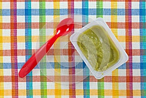 Baby food and spoon on a colorful place mat