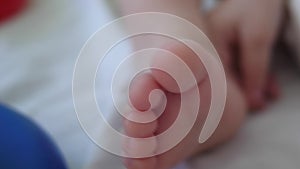 Baby foot close-up. Child in diapers plays with toys