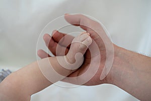 Father hand holding baby foot