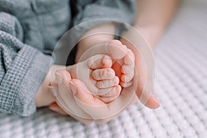 Baby foot in mom`s hands. The feet of a tiny newborn baby on a female hand shape close up