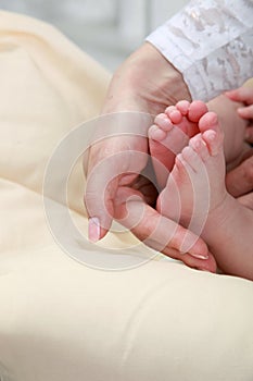 Baby foot in mother`s hands with care