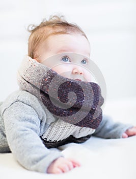 Baby in a frey knitted sweater and big brown scarf photo