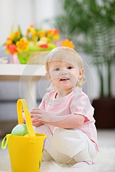 Baby gathering Easter eggs in basket