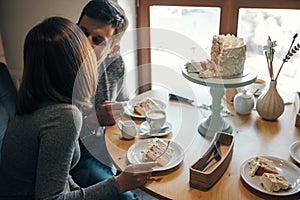 Baby gender reveal party. Happy stylish pregnant couple eating delicious cream cake at baby shower, with pink cream inside. Happy