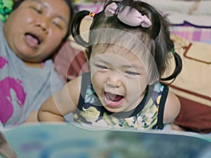 A baby girl, 2 years old, reading aloud, repeating after her auntie, a bedtime story