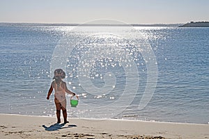 A baby girl admiring the ocean view and sun reflection on the water, Sydney, Australia