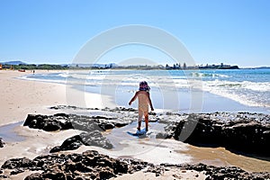 A baby girl admiring the ocean view and sun reflection on the water, Sydney, Australia