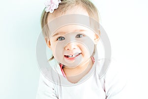 Baby girl with big eyes against the wall. Looking into camera and laughing