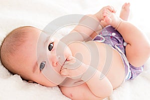 Baby girl biting her hand wearing ecologic cloth diaper