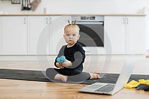 Baby girl in black wear sitting on mat with resistance band