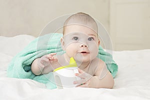 Baby girl boy wrapped in a towel holding a non-spill cup. Caucasian baby portrait soft focus