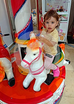 Baby girl on carousel horse.
